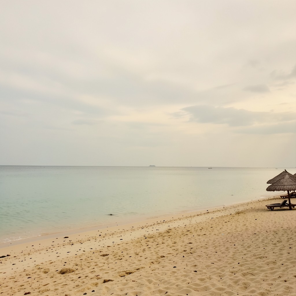 Ko Samui shoreline with calm water and sparse beach umbrellas